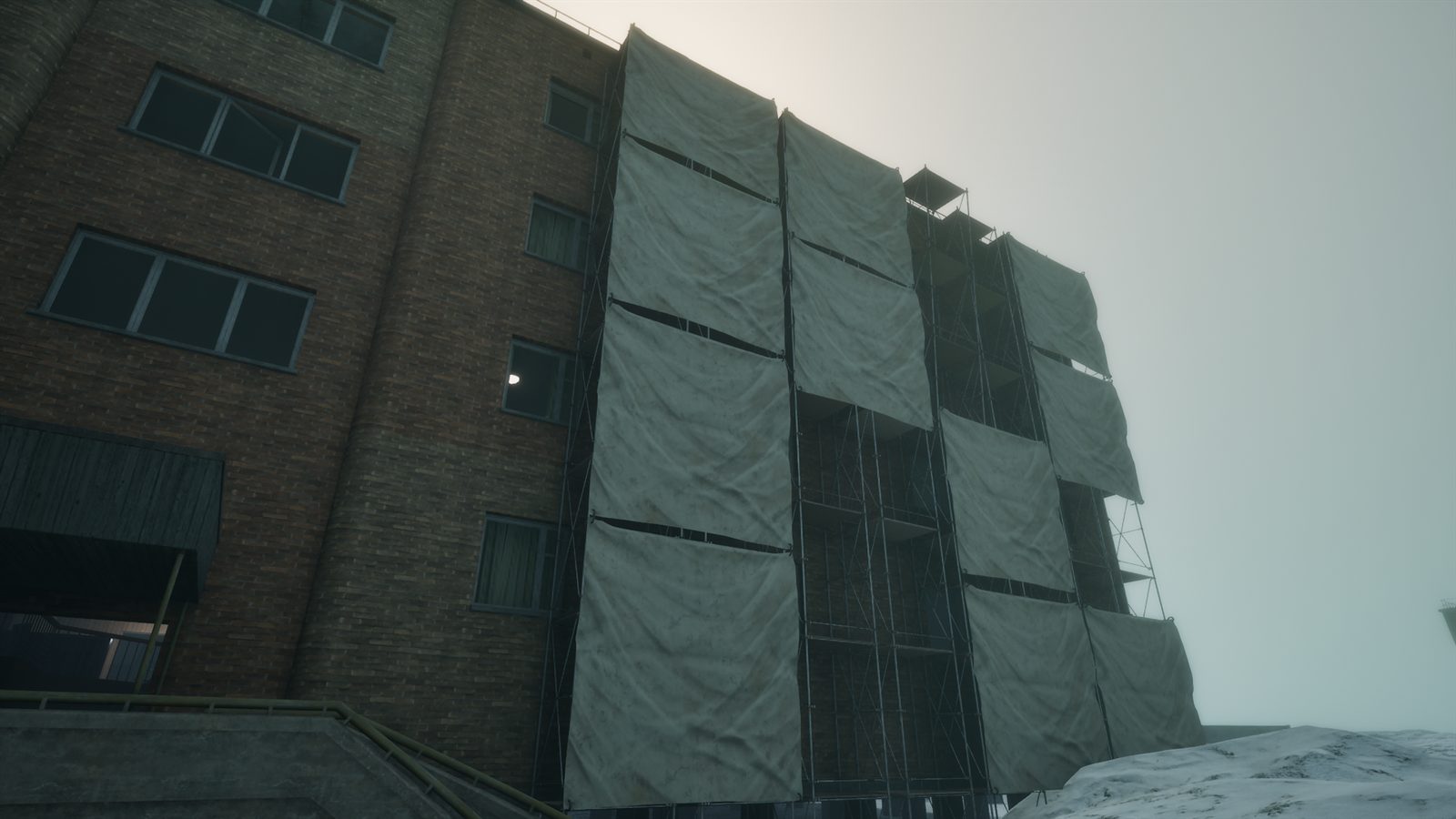 A concrete building wrapped in grey tarps under a white sky, with snow on the ground