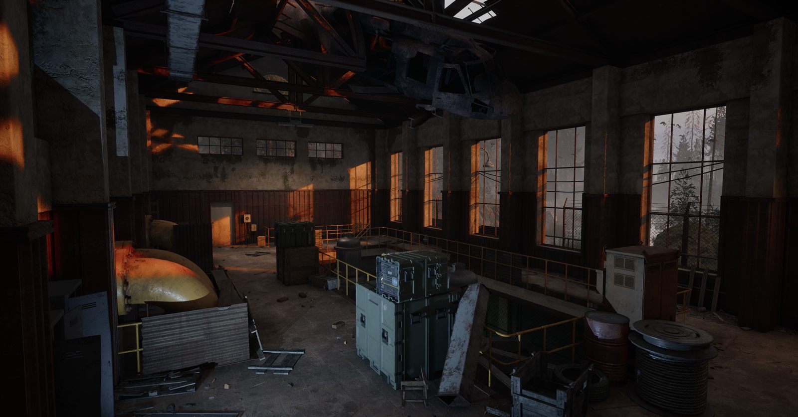 A tall industrial hall with rows of windows, a large orange machine and scattered equipment