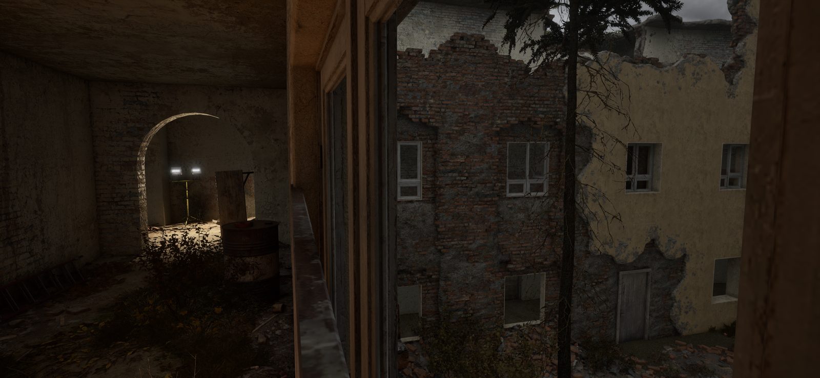 A view through a broken window onto a crumbling yellow brick courtyard with an arched passage